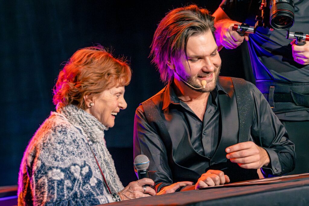Alex Boyer shares a moment of magic with a guest on stage.